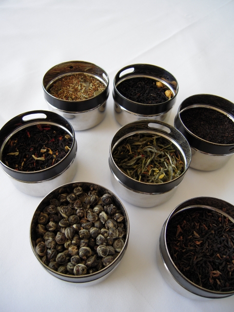 色々な茶葉と丸い紅茶缶がいくつもランダムに並んでいます